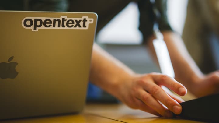 Mac-Laptop mit OpenText-Aufkleber