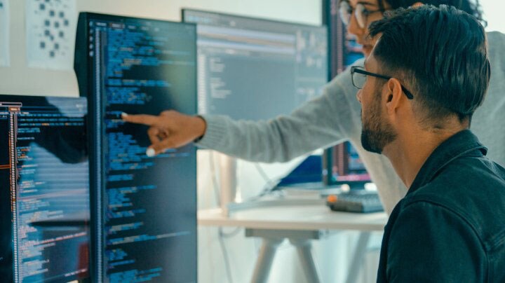 Personen, die Code auf Monitoren überprüfen