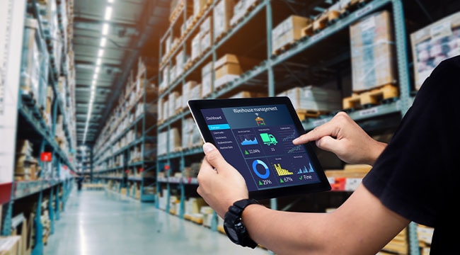 A person holding a tablet inside a warehouse